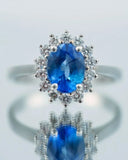 Sapphire and diamond ring with an oval blue gemstone surrounded by smaller diamonds.