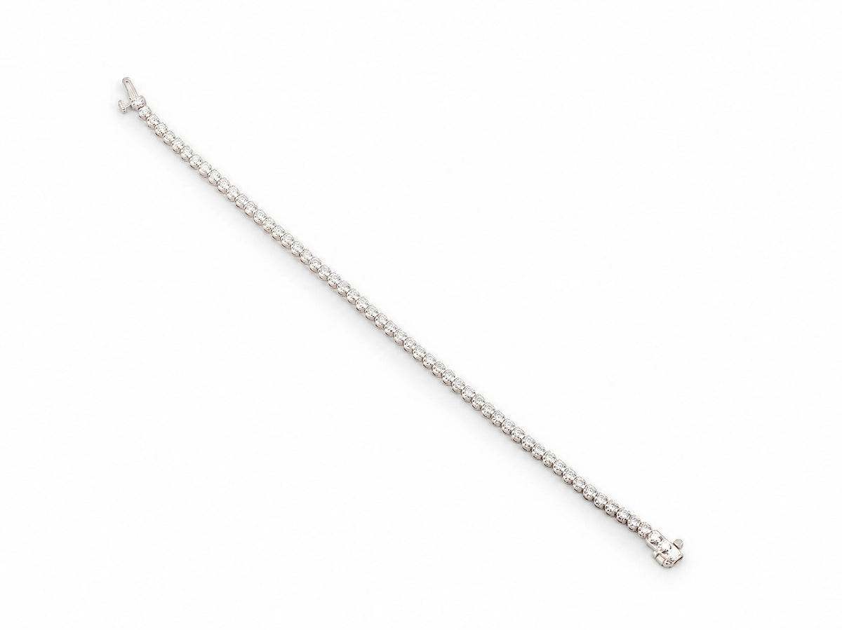 The tennis bracelet opened flat and laid out full length, the whole stone row visible with both parts of the box clasp at the ends