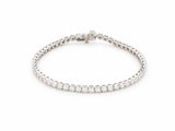 14K white gold tennis bracelet laid in an oval on white, one continuous row of round lab grown diamonds, box clasp at the top