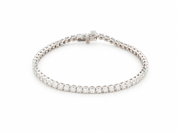 14K white gold tennis bracelet laid in an oval on white, one continuous row of round lab grown diamonds, box clasp at the top