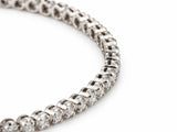 Macro view of the bracelet curving across the surface, individual four-prong settings and the hinge joints between them in focus