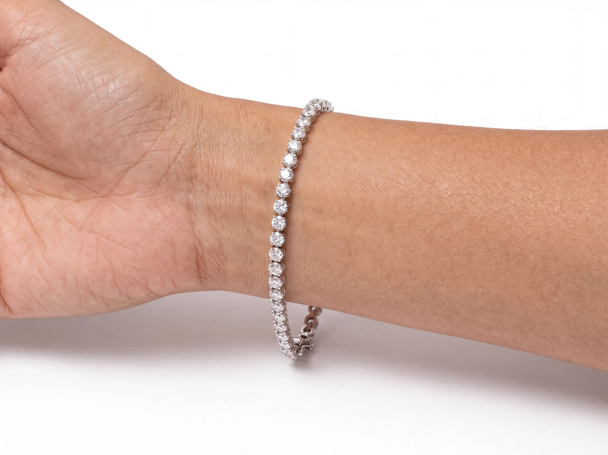 The 14K white gold diamond tennis bracelet worn on a wrist, the row of stones across the top of the wrist with the hand and forearm in frame