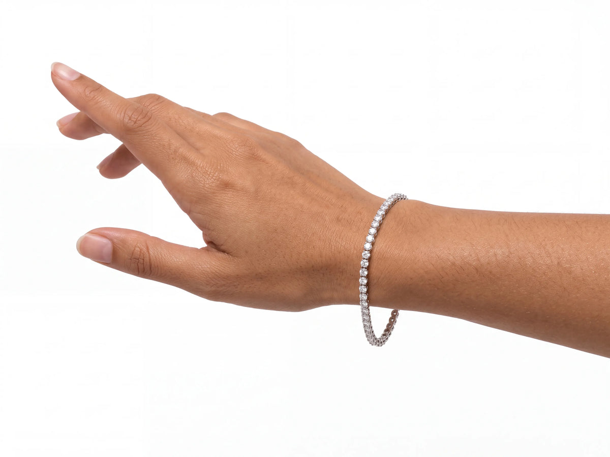 The tennis bracelet on a model's wrist seen from the back of the hand, the diamond row face-on where it crosses the wrist