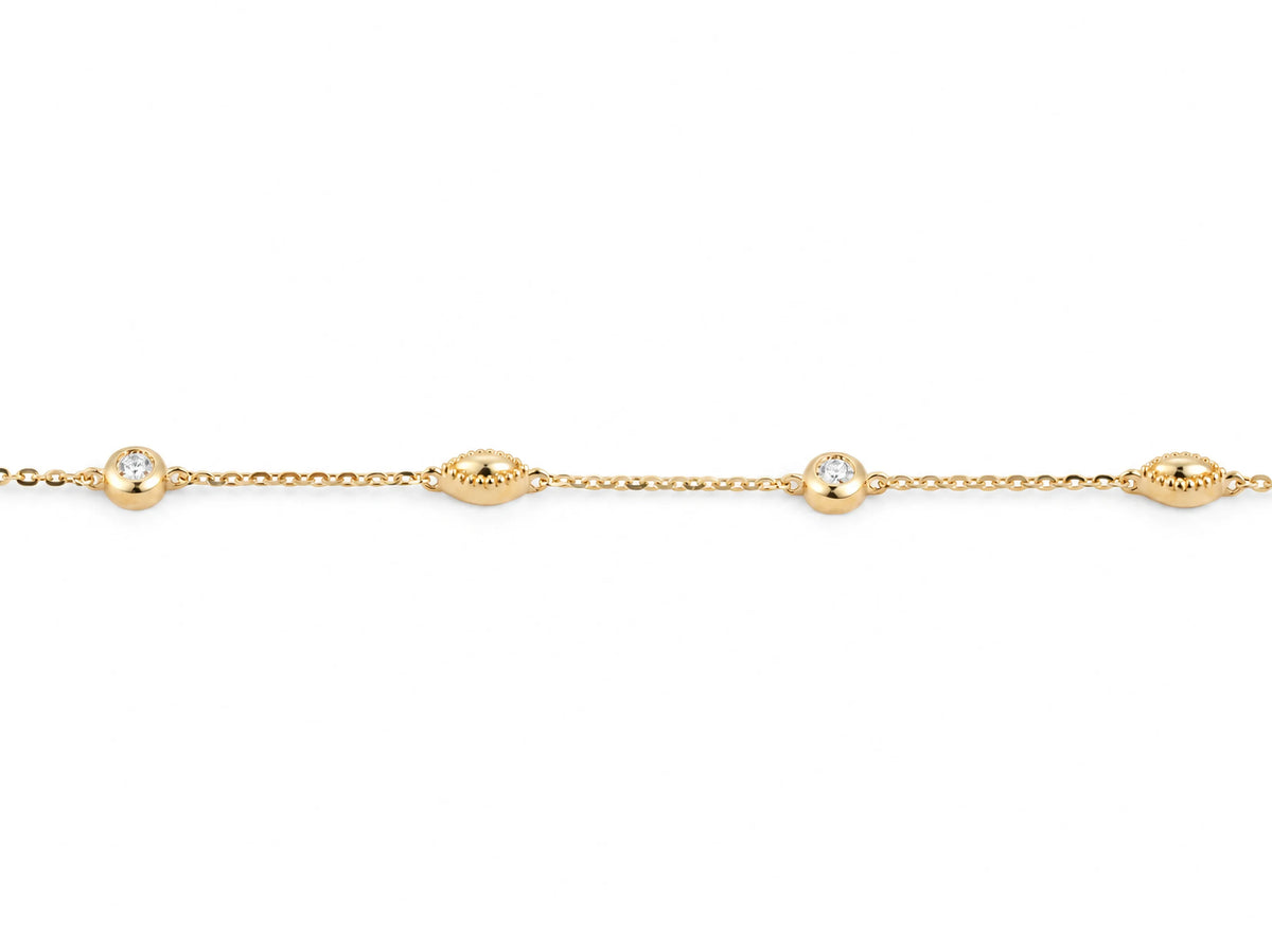 Close view of the alternating stations on the 14K yellow gold cable chain, a round diamond in a polished bezel beside a gold bead with a milgrain rim