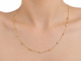 The diamond station necklace worn on the upper chest with the lowest station below the collarbone, the yellow gold chain against bare skin