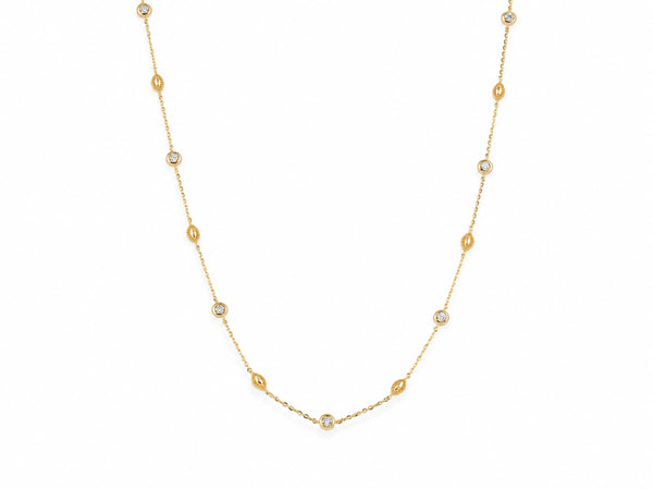14K yellow gold station necklace laid out on white, round diamonds in gold bezels alternating with milgrain gold beads along the fine cable chain