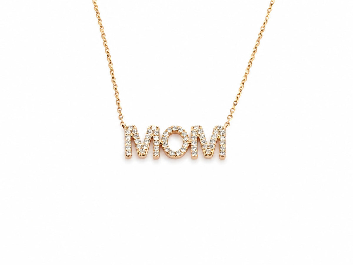Close view of the MOM pendant, each letter pavé set with small round diamonds, the chain joining the outer edges of the two M's