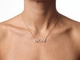 The MOM pendant worn front on over the upper chest just below the collarbone, the fine yellow gold chain centred over bare skin