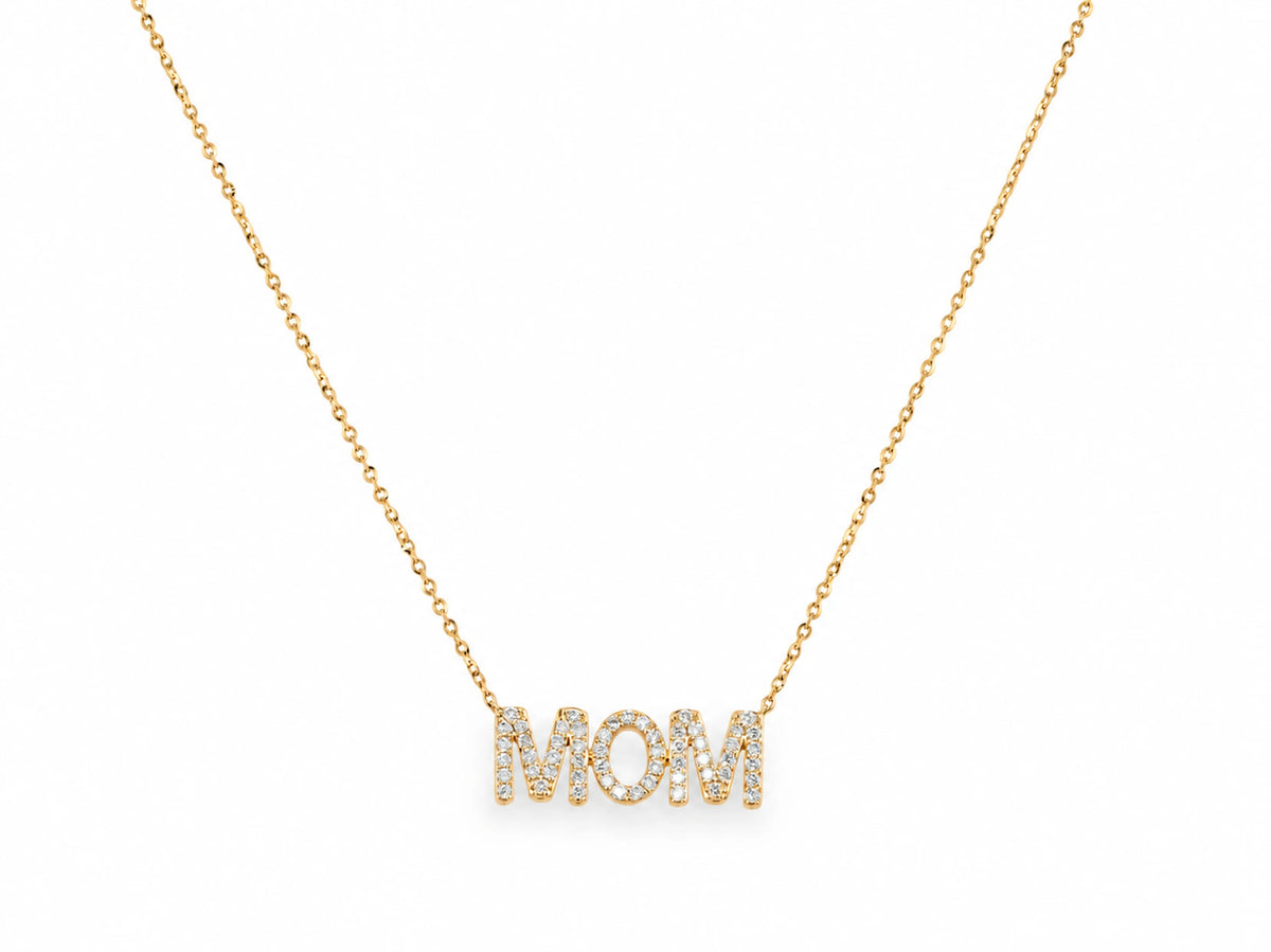 The MOM diamond pendant at the base of a fine 14K yellow gold cable chain on white, the chain curving up and out of the top of the frame