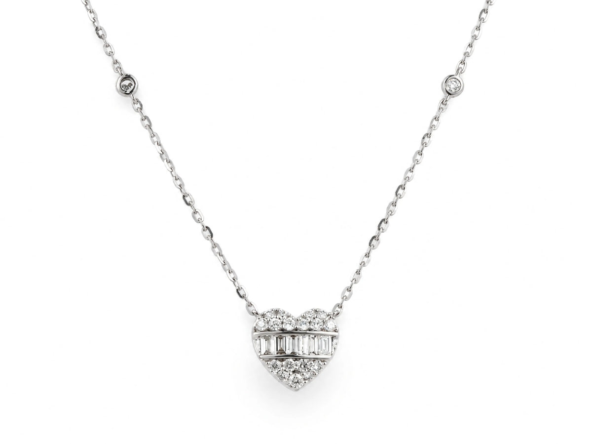 A 14K white gold diamond heart necklace laid out flat, its face crossed by a channel of baguette-cut diamonds, on a fine cable chain.