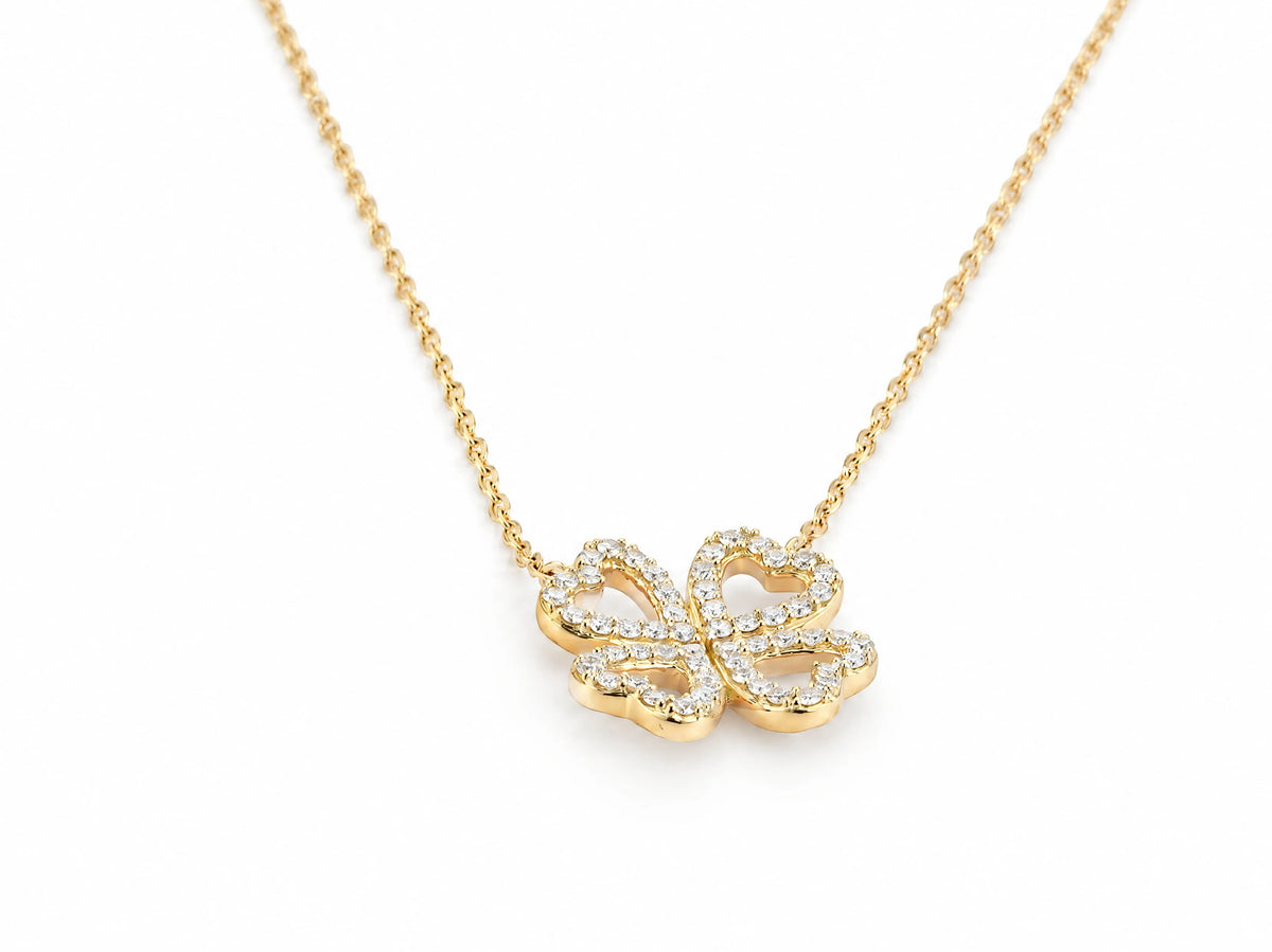 Close view of the clover pendant hanging from the fine yellow gold chain, the open heart leaves traced with small round lab grown diamonds