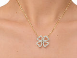 The clover pendant worn on the upper chest just below the collarbone, the yellow gold chain against bare skin