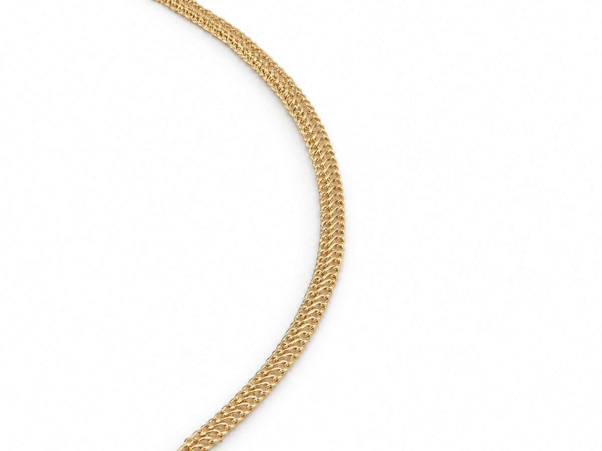 Close-up detail of the woven chevron link pattern on the gold chain necklace