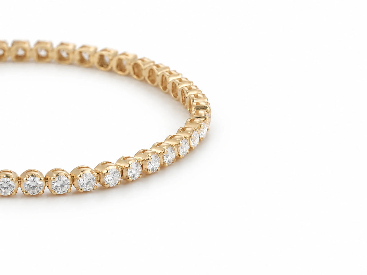 Close view of the round lab grown diamonds and their yellow gold settings on the tennis bracelet