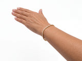 14K yellow gold diamond tennis bracelet worn on a wrist, the stone row crossing the top of the wrist