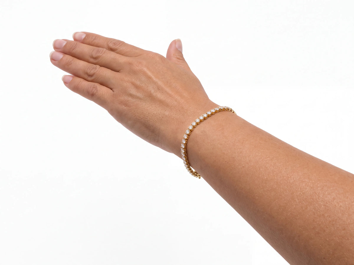 14K yellow gold diamond tennis bracelet worn on a wrist, the stone row crossing the top of the wrist