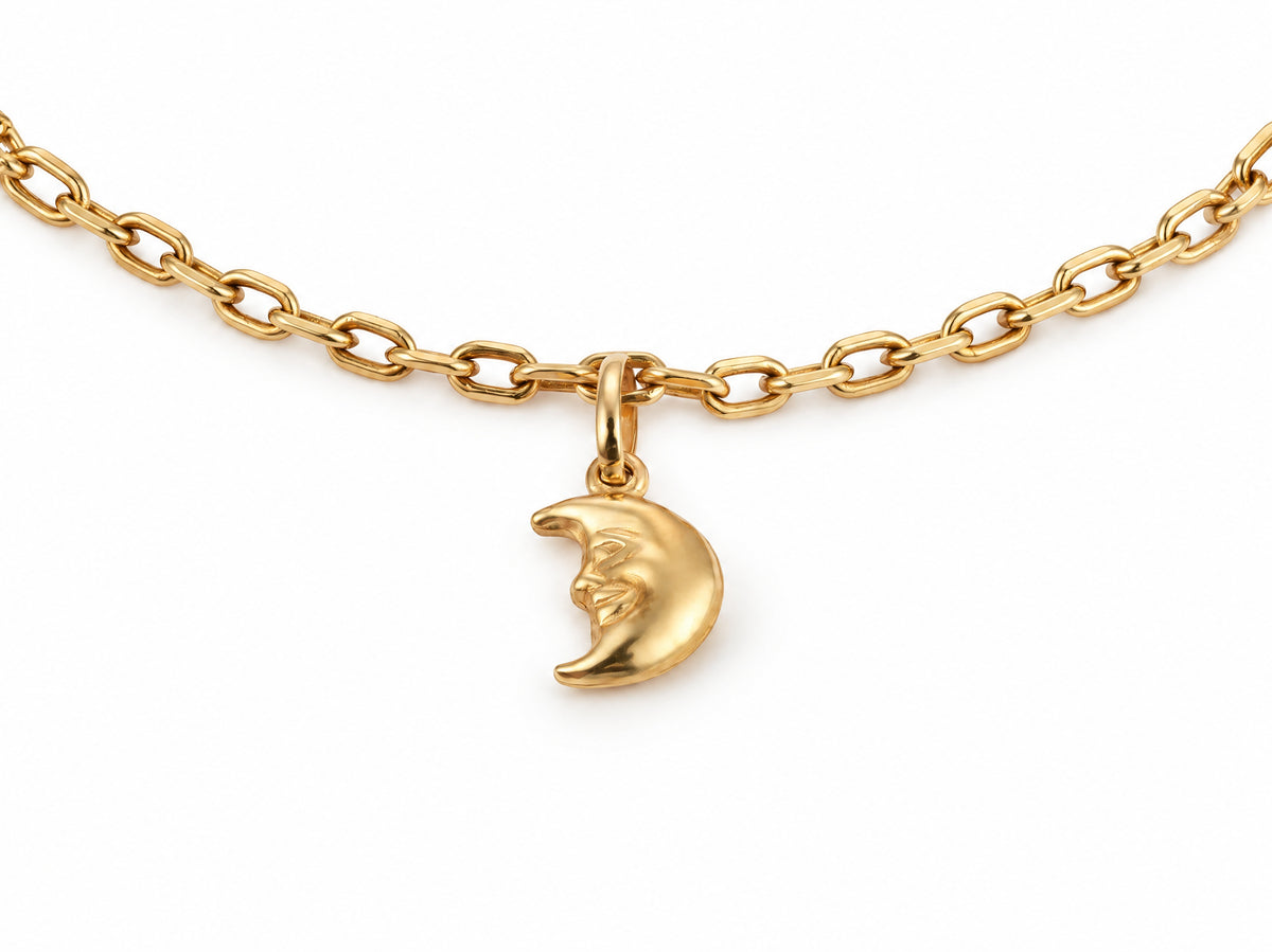 Close-up of the gold crescent moon charm with its face in profile