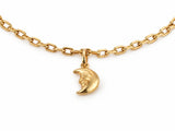 Close-up of the gold crescent moon charm with its face in profile