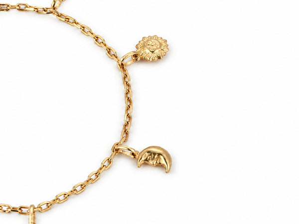Overhead view of the gold charm bracelet with a sun charm and a crescent moon charm