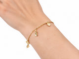 Gold charm bracelet worn on the wrist with the sun and moon charms visible