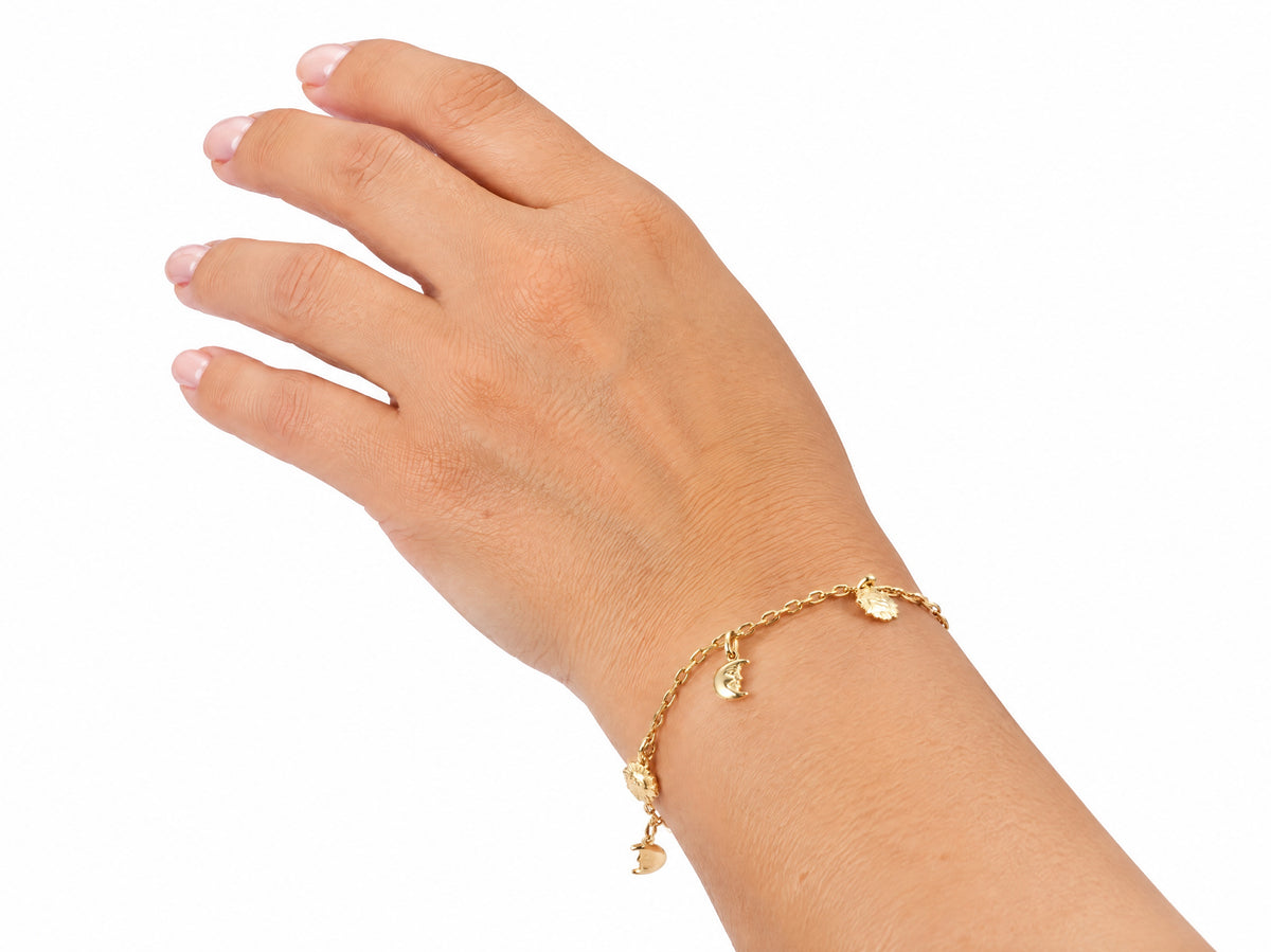 Gold charm bracelet worn on the wrist, second view
