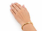 18K yellow gold bracelet worn on the hand, lifestyle shot on a white background