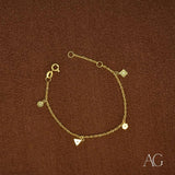 18K gold charm bracelet with triangular, hexagonal, square and circular clear stone charms on brown background