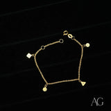 18K gold bracelet with square, triangle, hexagon and circular charms on delicate chain, black background