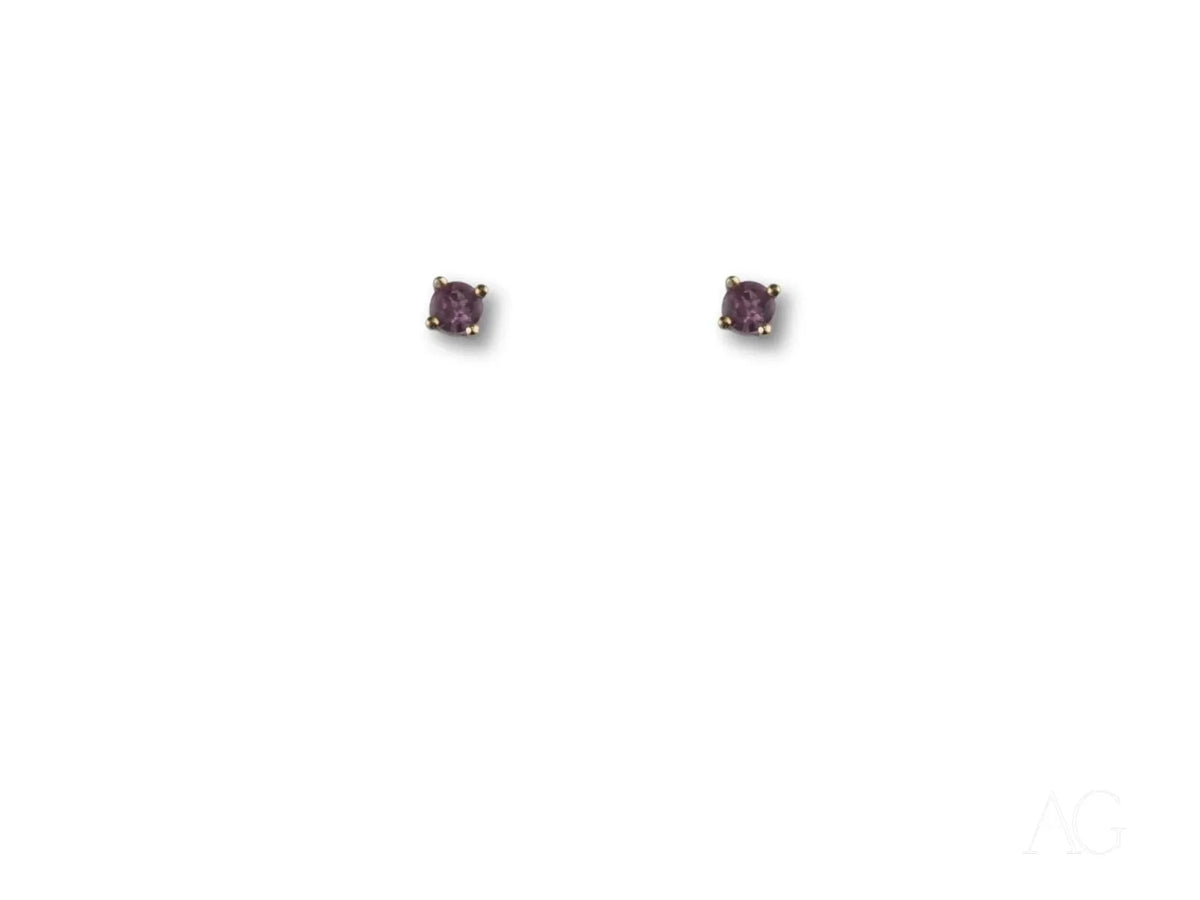 Pair of 18K gold stud earrings with purple CZ stones in four-prong settings, top view
