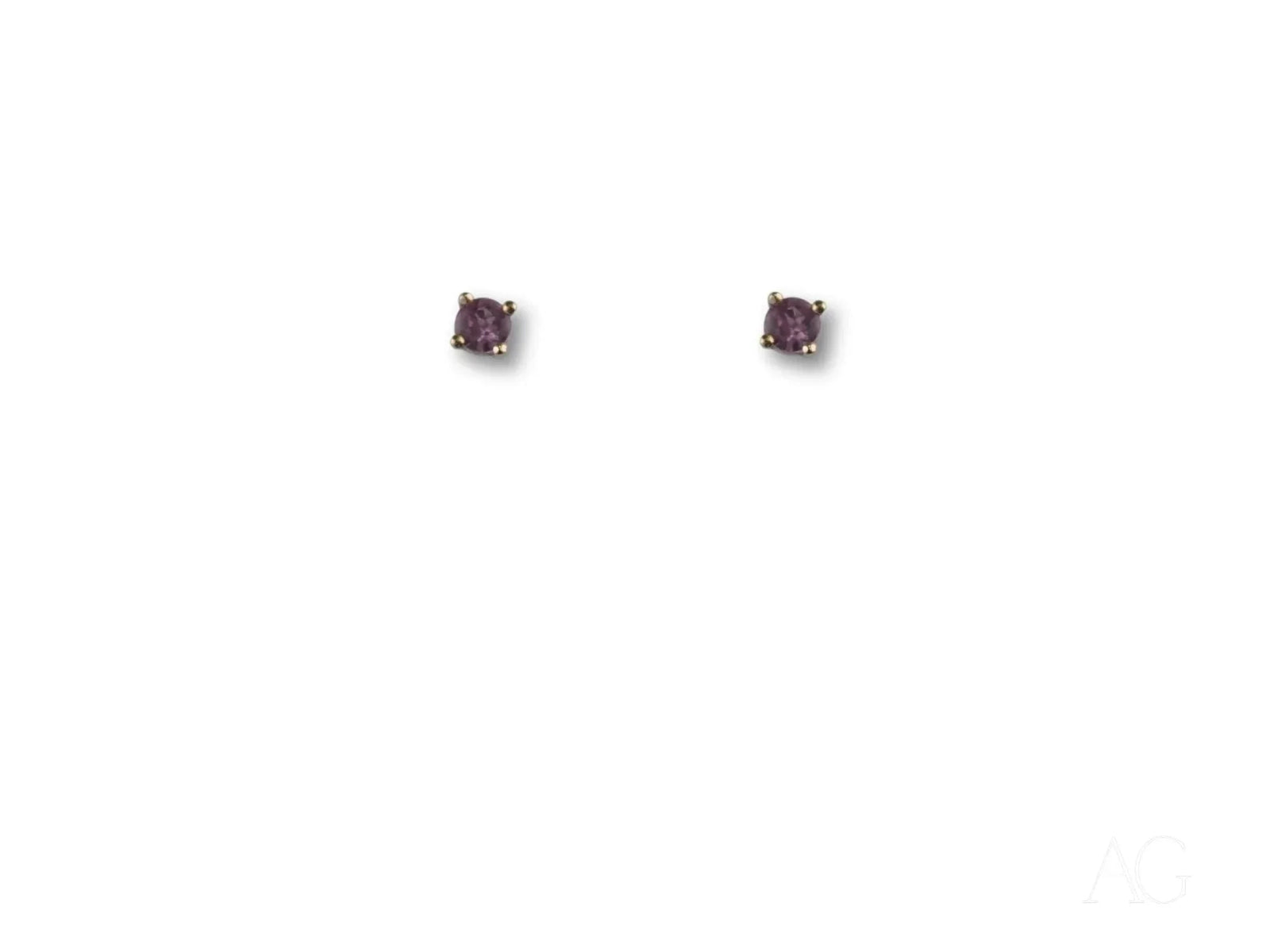 Pair of 18K gold stud earrings with purple CZ stones in four-prong settings, top view