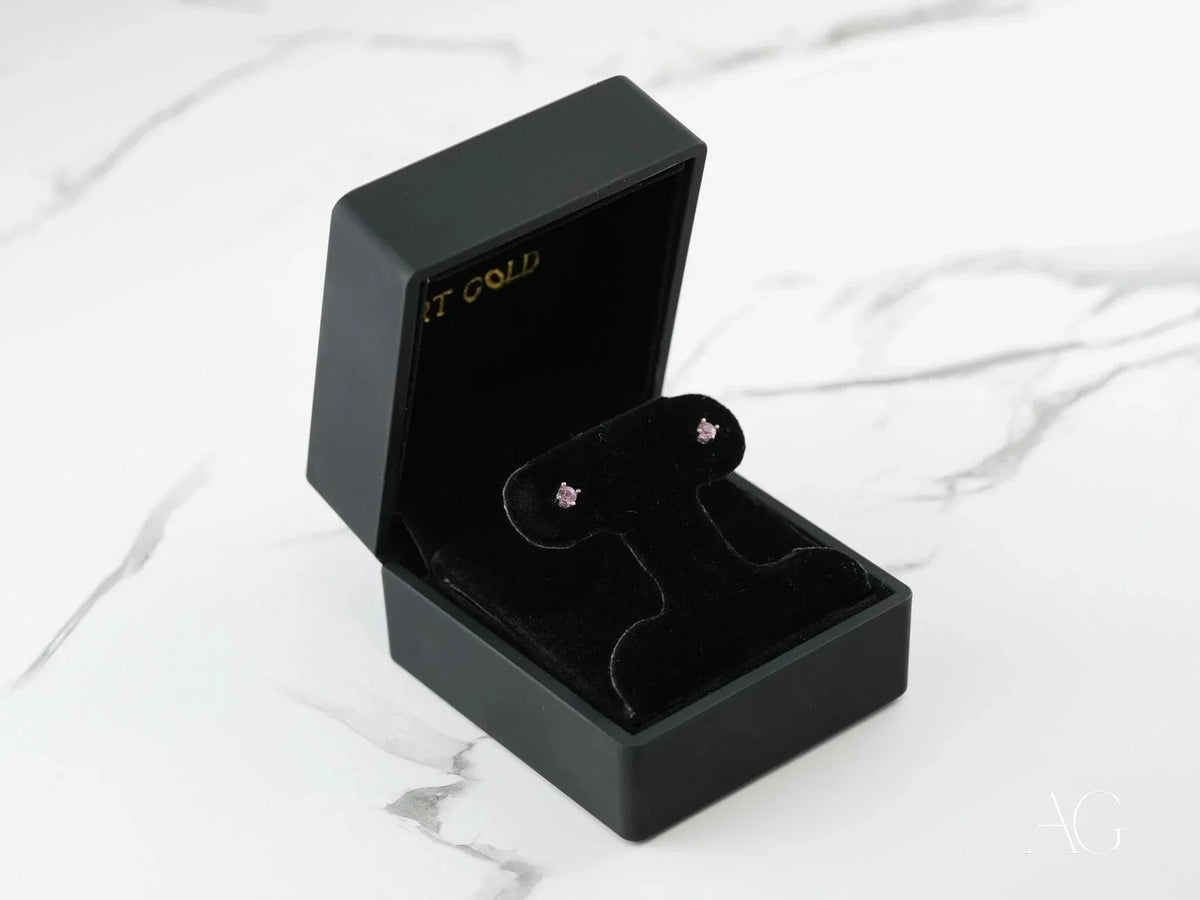 Pair of 18K gold stud earrings with purple CZ stones in four-prong settings