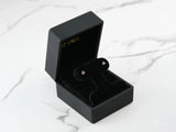 Pair of 18K gold stud earrings with purple CZ stones in four-prong settings