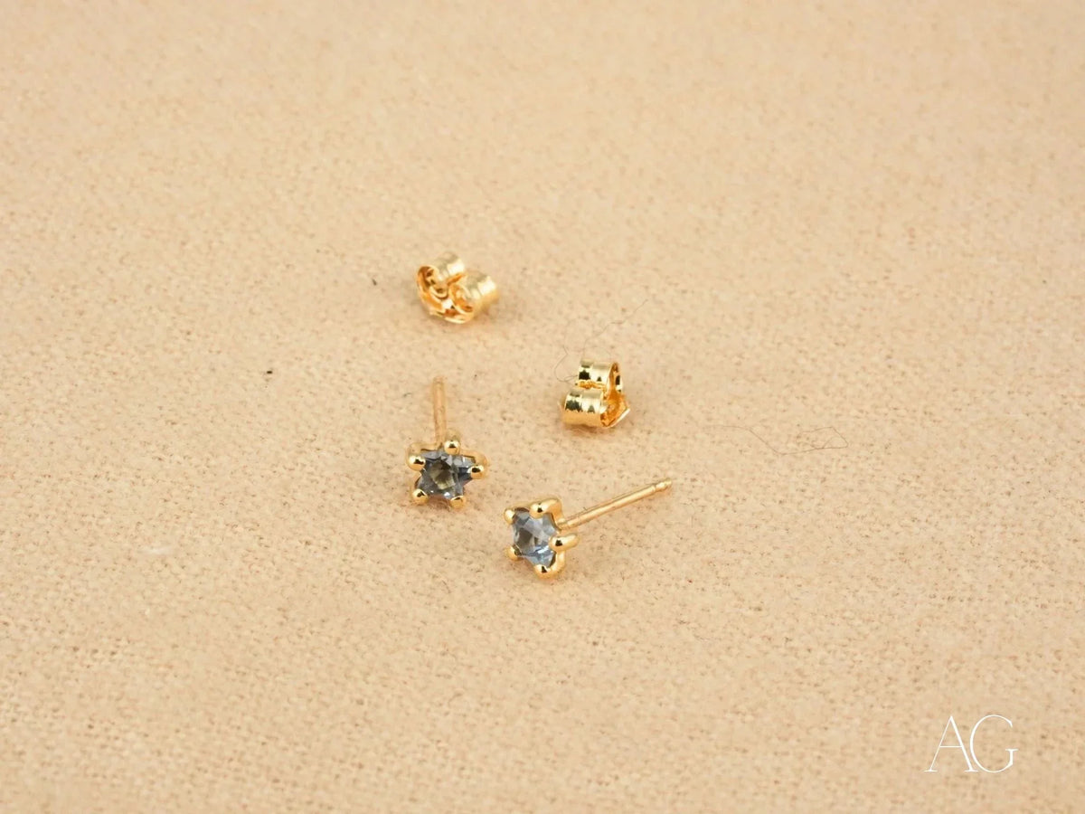 Two 18K gold stud earrings with blue stones and butterfly back closures