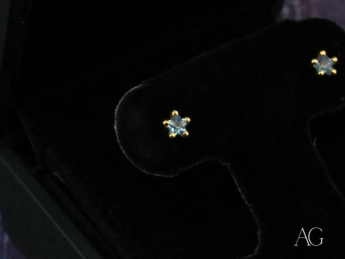 Close-up of 18K gold stud earrings with blue stones in six-prong star settings