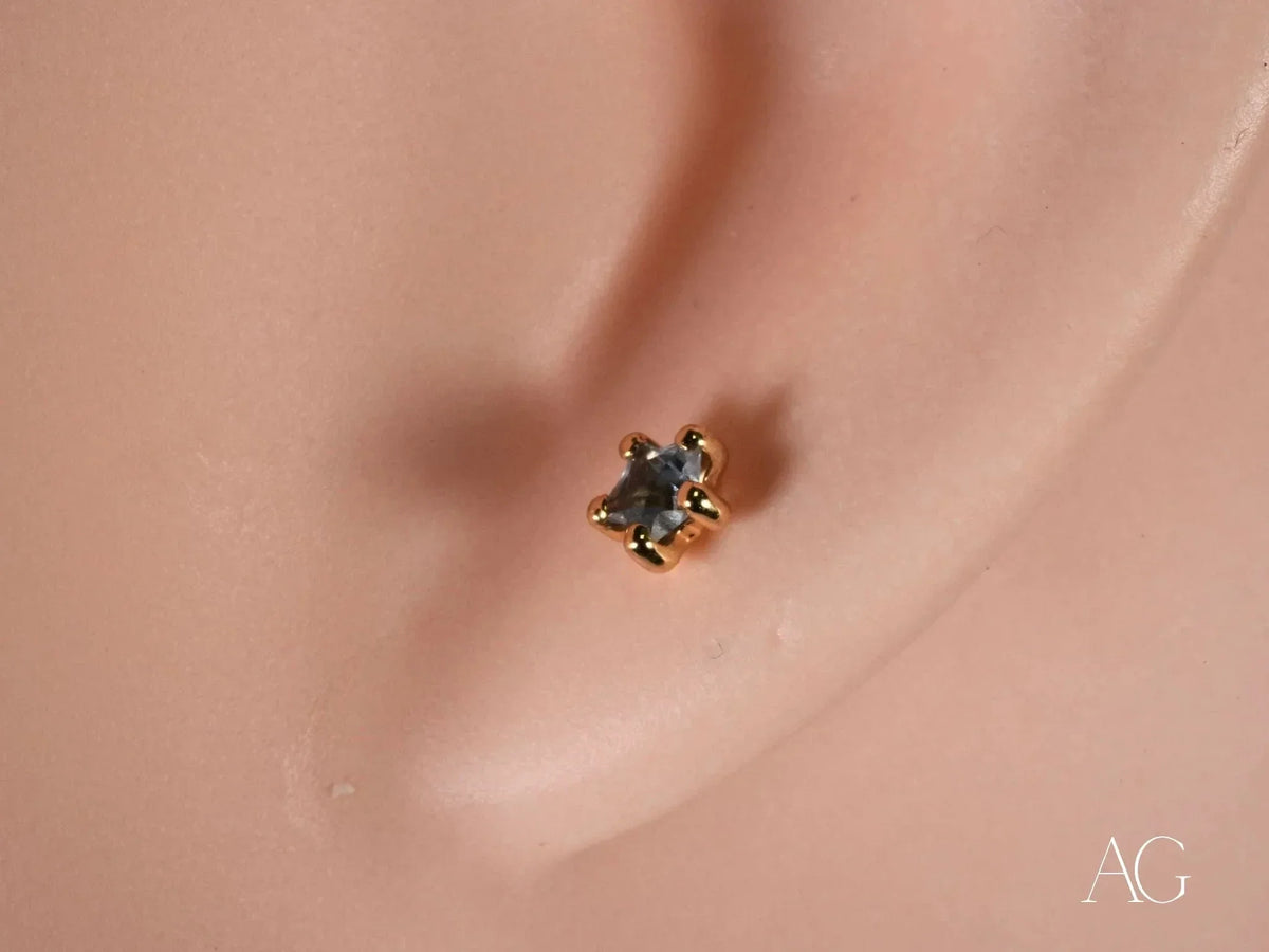Close-up of 18K gold stud earring with blue stone in six-prong star setting