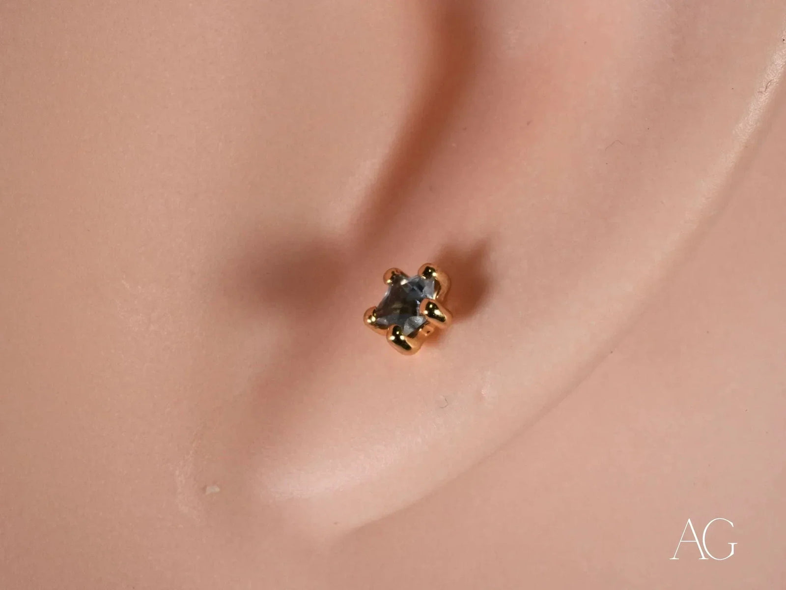 Close-up of 18K gold stud earring with blue stone in six-prong star setting