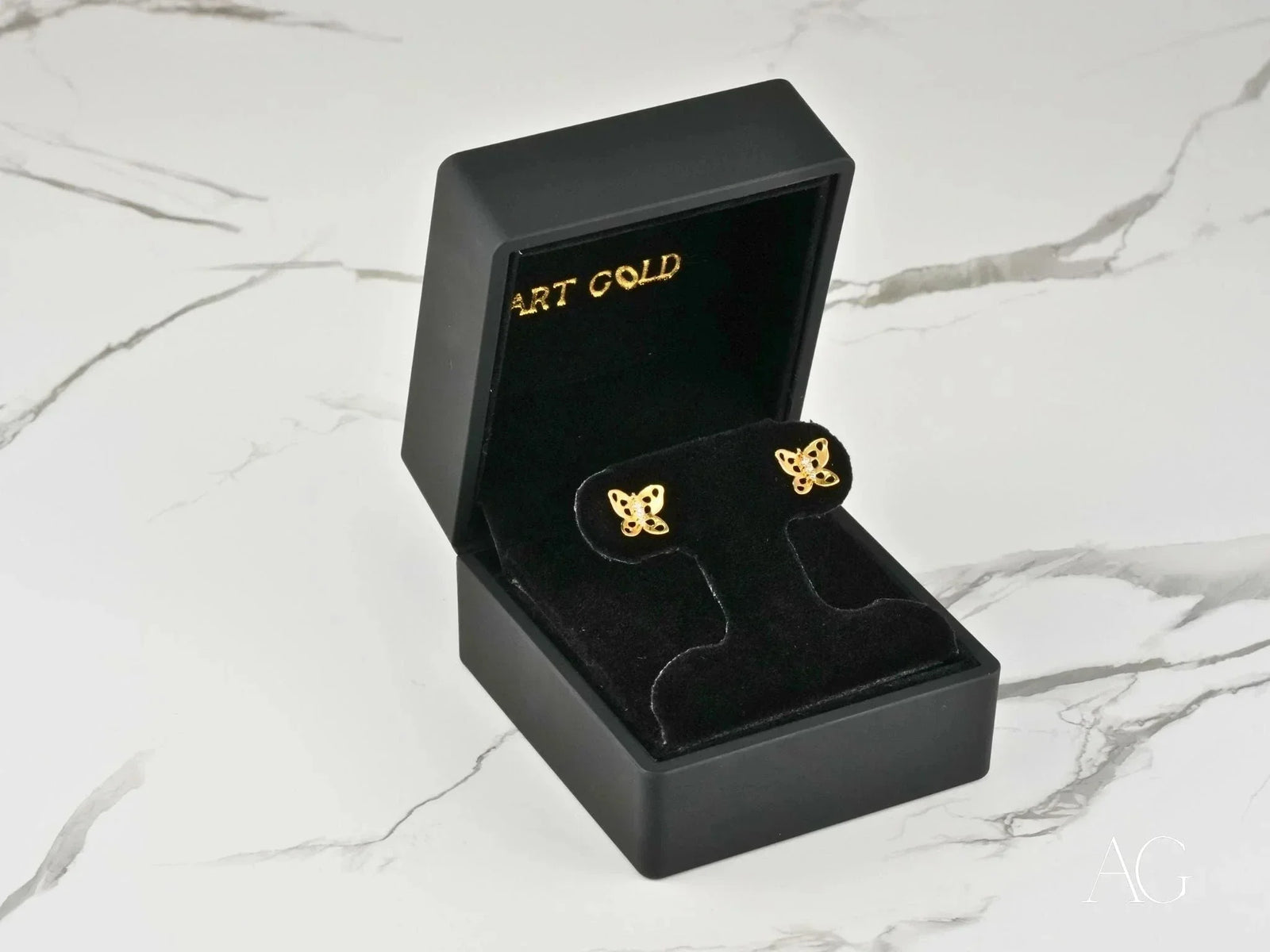 Two 18K gold butterfly stud earrings with cutout wings and cubic zirconia centers, top-down view