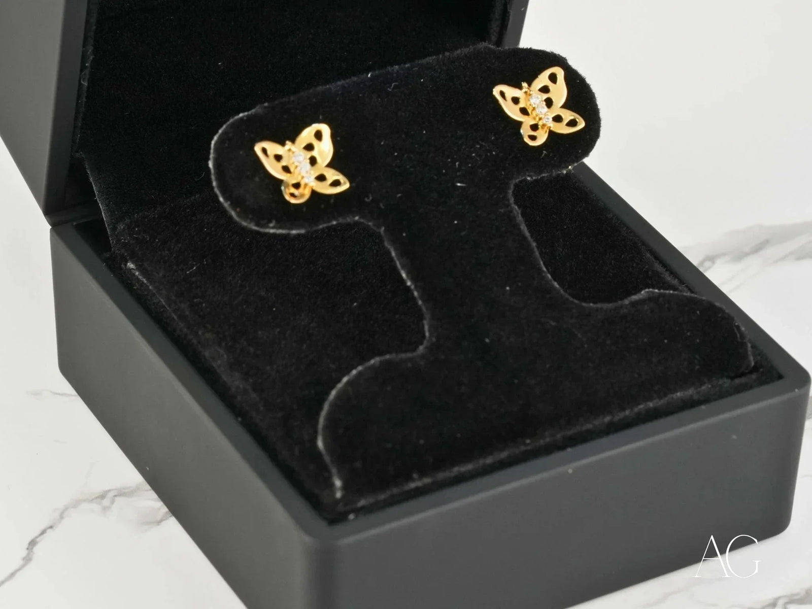 Pair of 18K gold butterfly earrings with openwork wings and central CZ stones, angled close-up view