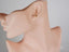 Elegant 18K Gold Pearl Stud Earrings with a small animal-shaped gemstone on a mannequin ear