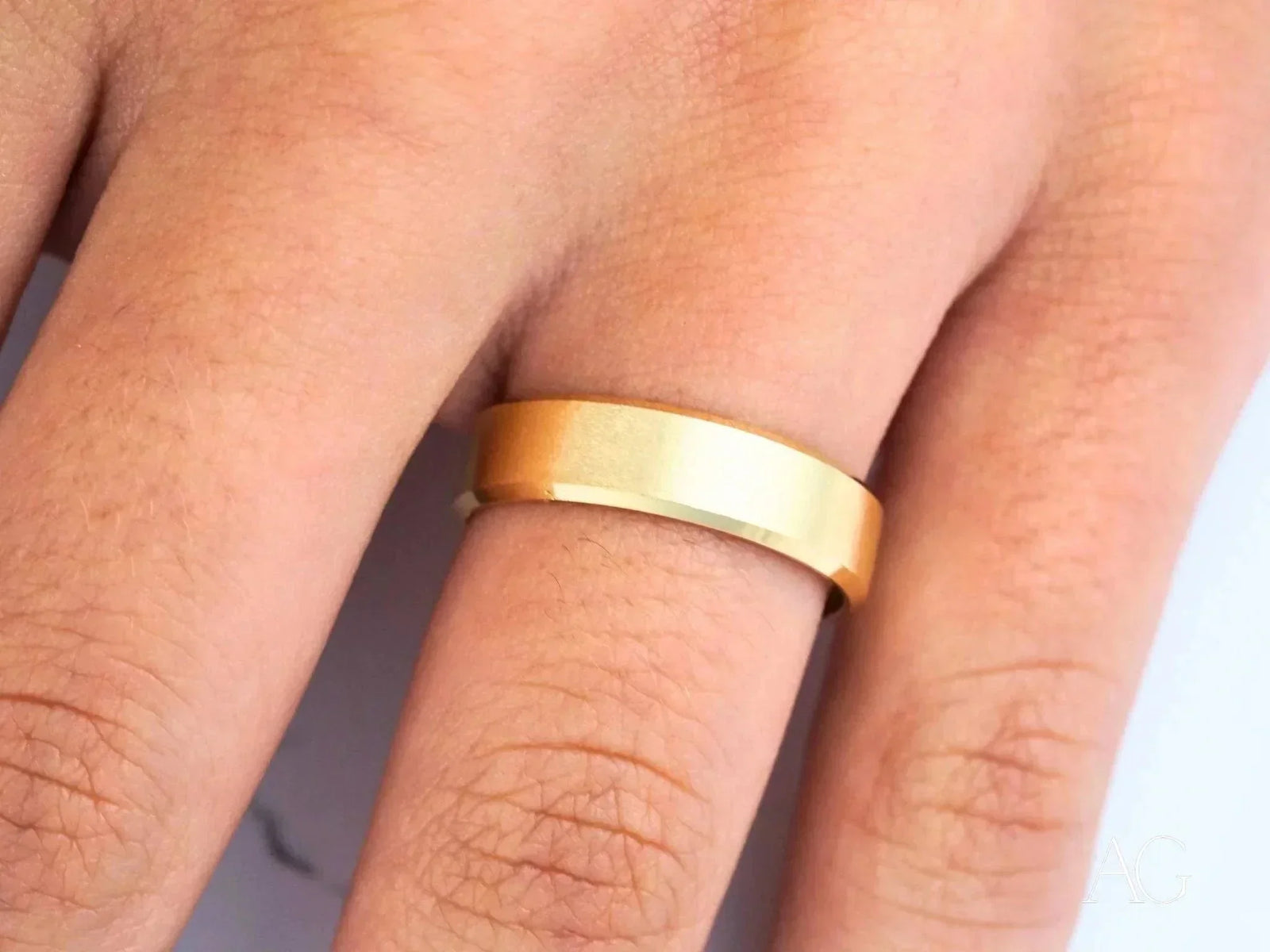 Shiny 18k solid gold wedding band on finger, modern elegance