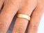 Shiny 18k solid gold wedding band on finger showcasing modern art gold jewelry style