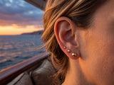 18k gold ball stud earrings in graduated sizes on ear