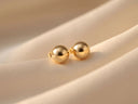 18k gold ball stud earrings on cream fabric