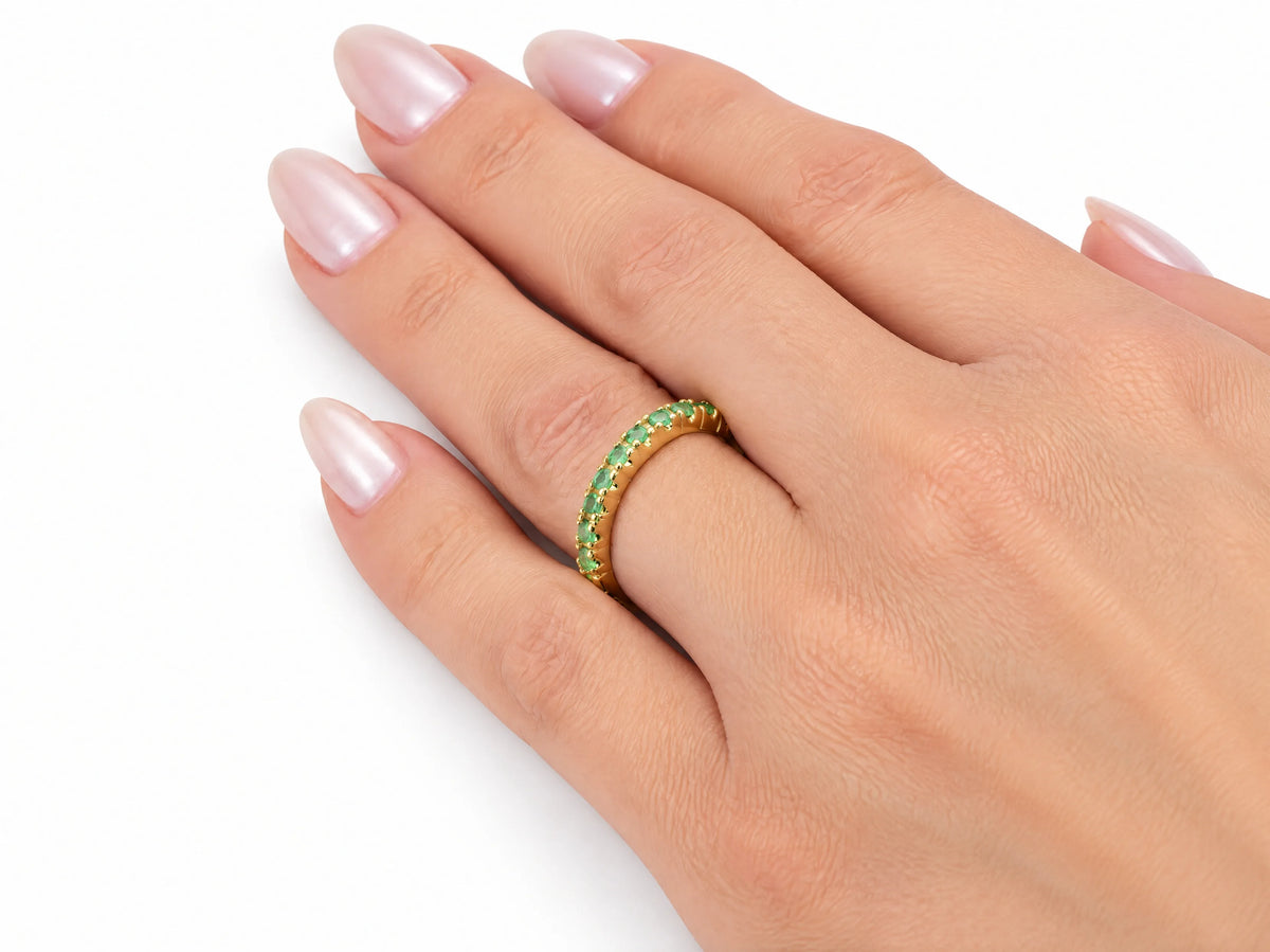 ArtGold 18K yellow gold half eternity emerald band worn on the finger, close view of the emerald row
