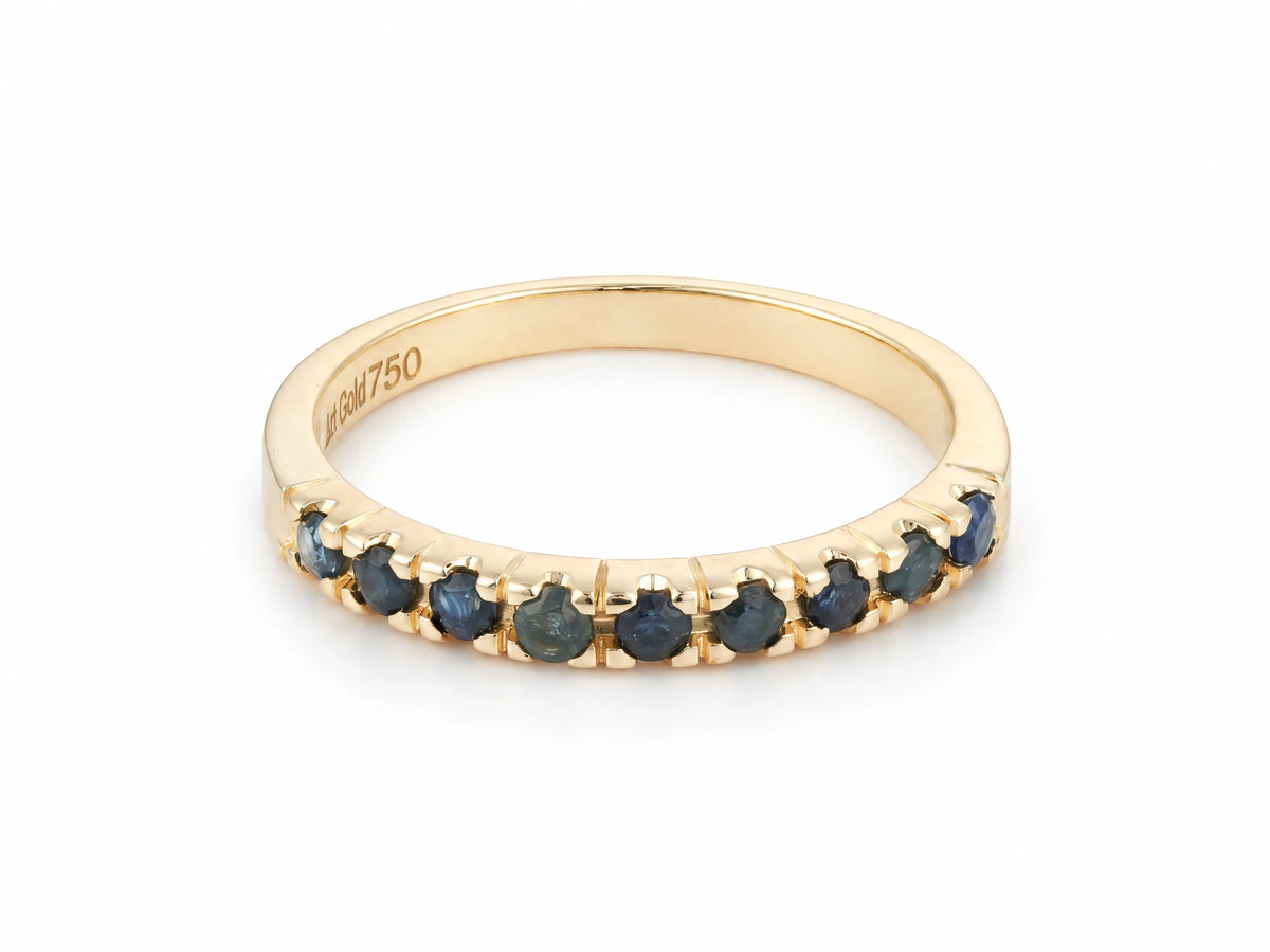 ArtGold 18K yellow gold half eternity band set with nine round dark blue sapphires in a single row, front view of the shared-prong setting and polished band