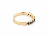 ArtGold 18K yellow gold half eternity sapphire band, three-quarter view showing the row of nine round dark blue sapphires and the smooth plain back of the band
