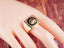 Gold-toned signet ring with black enamel Medusa head and horse shoe motif
