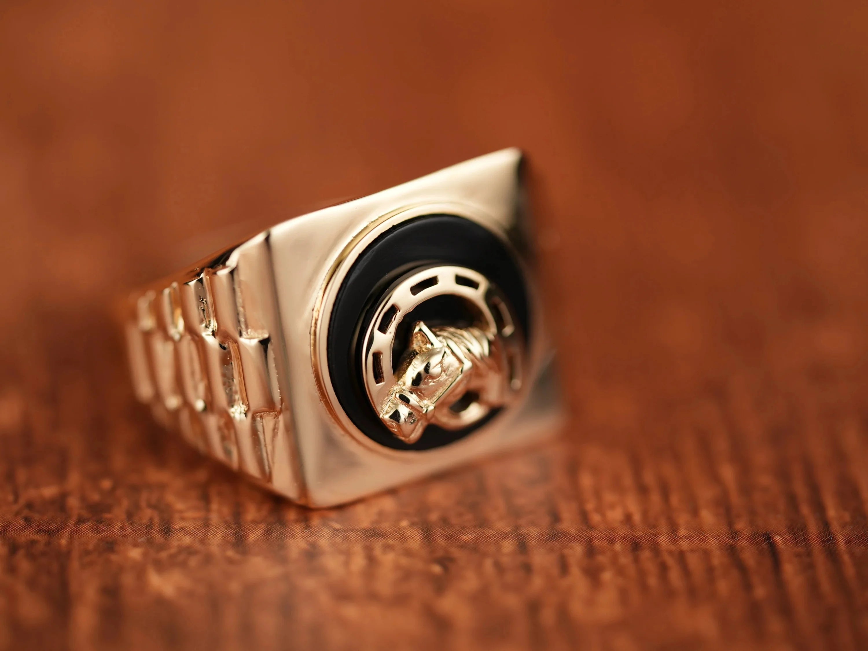 Gold ring with black onix horse shoes face featuring horse shoe motif and horse head design