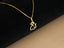 Solid 18 k gold cat pendant displayed on a black background; the polished cat-shaped charm is attached to a delicate chain.
