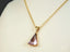 Gold-toned necklace featuring an Amethyst Trillion Pendant with a pink gemstone